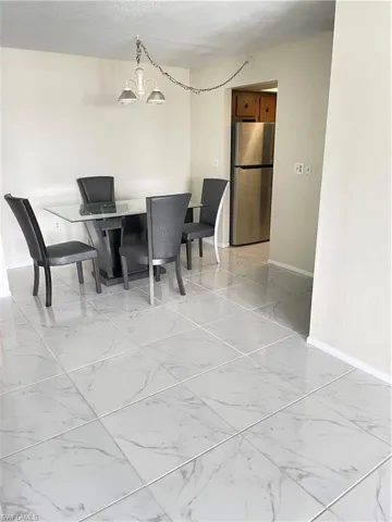 Tiled dining room featuring a notable chandelier and a textured ceiling