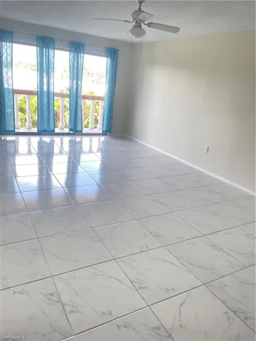 Unfurnished room with a textured ceiling, ceiling fan, and light tile floors