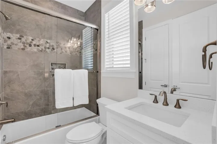 Full bathroom featuring vanity, combined bath / shower with glass door, and toilet
