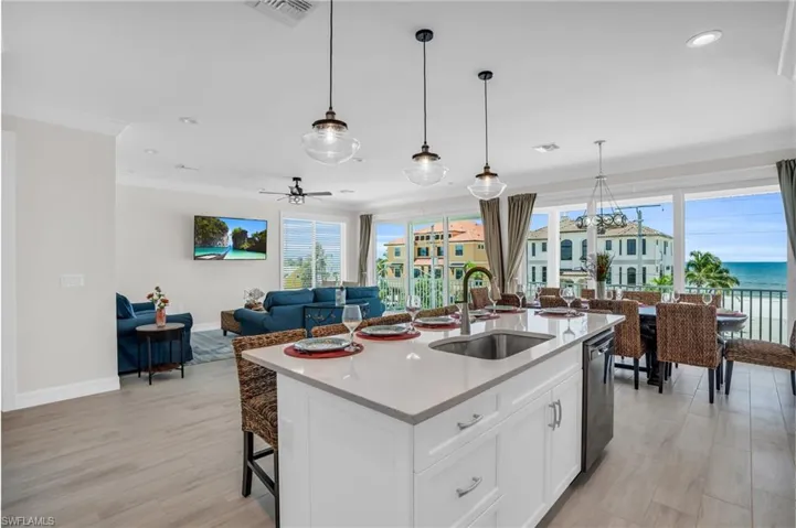 Kitchen with with LVP wood-style flooring, a water view, sink, pendant lighting, and a center island with sink