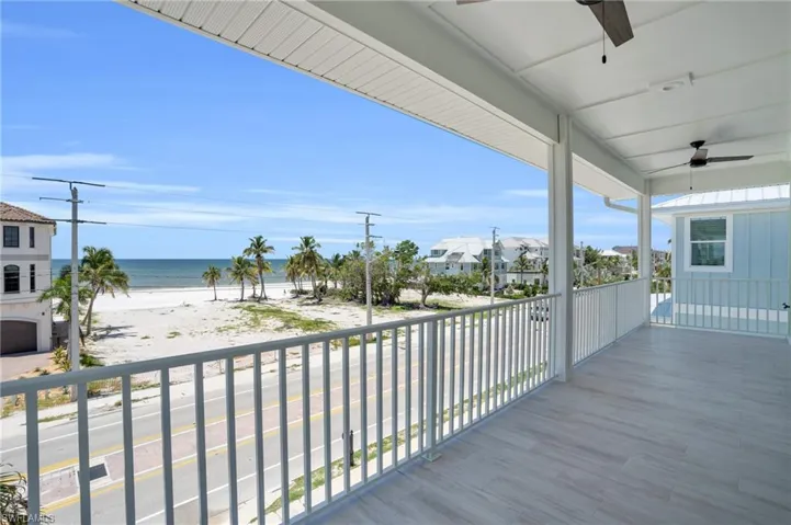 Balcony featuring a beach view, a water view, and ceiling fan
