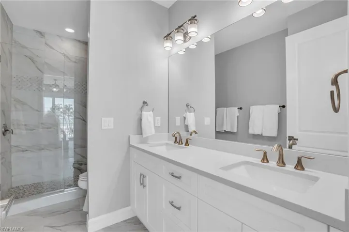 Bathroom featuring double vanity, tile patterned floors, a shower with door, and toilet