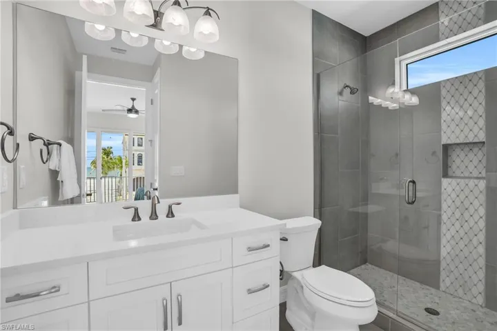 Bathroom featuring plenty of natural light, vanity, a shower with door, and toilet