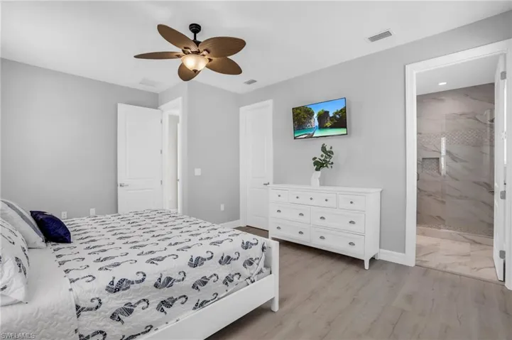 Bedroom featuring ensuite bathroom, light wood-type flooring, and ceiling fan