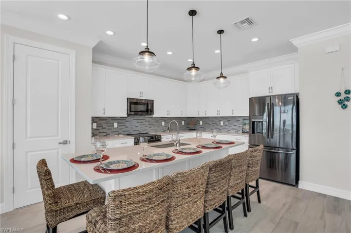 Kitchen with decorative backsplash, stainless steel appliances, with LVP wood-style flooring, and a kitchen breakfast bar