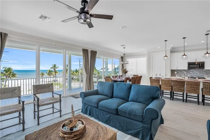 Living room featuring ceiling fan, a water view, crown molding, sink, and with LVP wood-style flooring