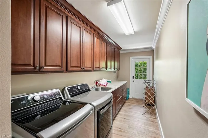 Upper and lower cabinetry with integrated sink, wood-finish flooring, and crown molding