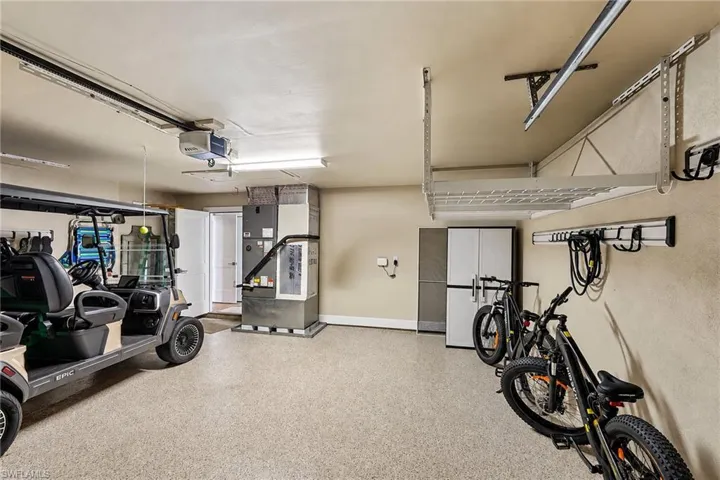 Garage featuring a durable epoxy floor, overhead storage racks, built-in cabinetry, and wall-mounted organization systems