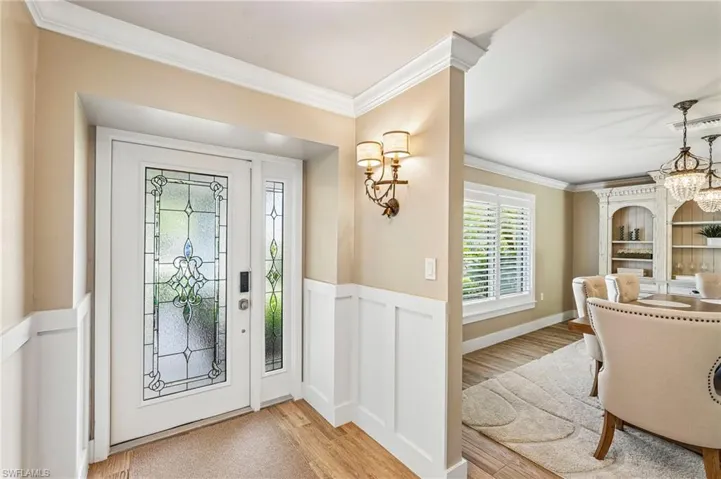 Entryway featuring a decorative glass front door, side panel, and wainscoting