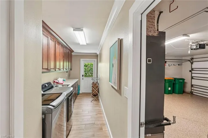 Laundry area featuring wood-finish flooring, upper cabinetry, and a countertop with an undermount sink