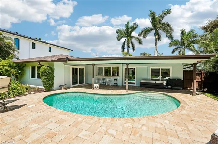 Kidney-shaped swimming pool surrounded by a paver patio