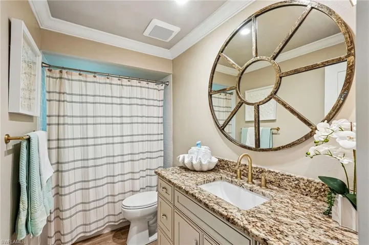 Granite-finish countertop, single basin sink, decorative wall mirror, and built-in vanity cabinetry