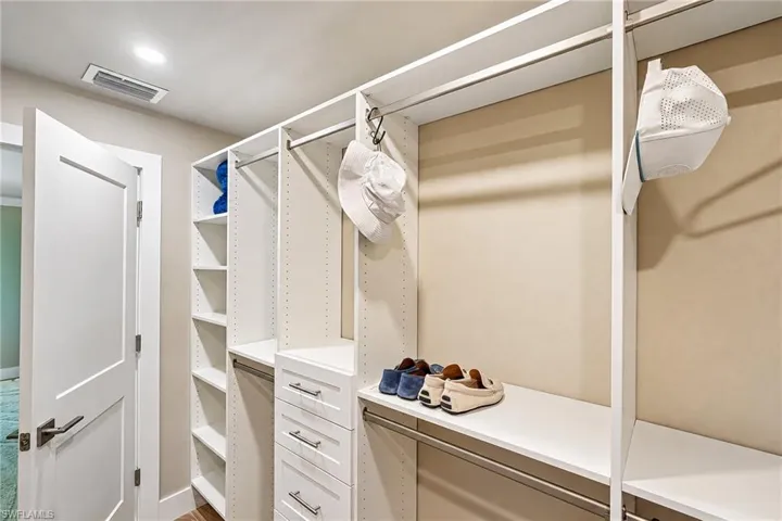 Custom closet system featuring multiple hanging rods, adjustable shelving, and built-in drawers with modern pulls
