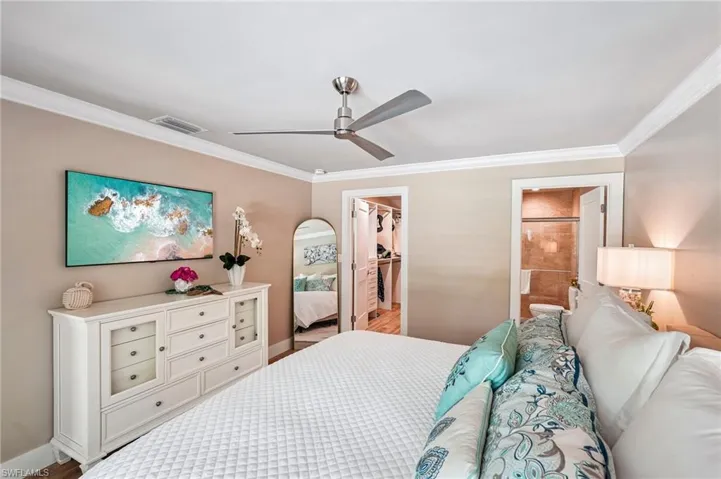 Ceiling fan with brushed nickel finish, crown molding, and a walk-in closet with built-in shelving