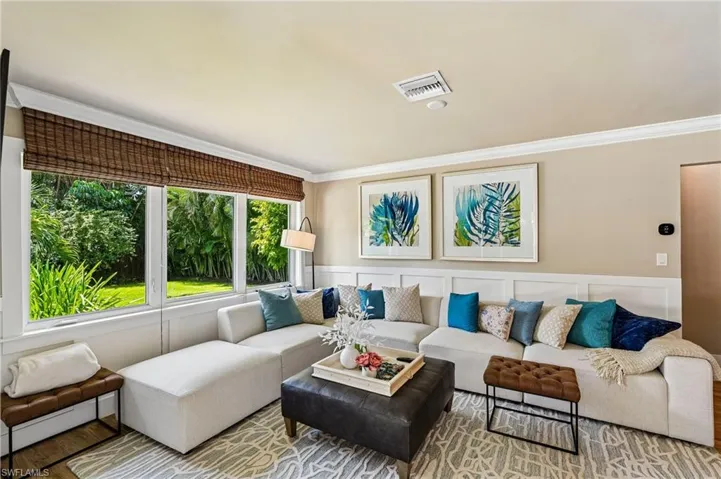 Expansive windows with woven wood shades, crown molding, and wainscoting