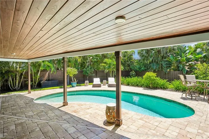 Covered patio with a wood-finish ceiling, paver patio, integrated lighting, and a kidney-shaped pool with a surrounding paver deck