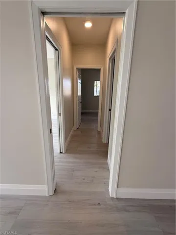 Corridor with baseboards and light wood-style floors