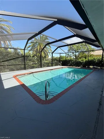 Outdoor pool featuring a sunroom, glass enclosure, and a patio