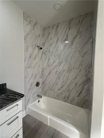 Full bathroom featuring  shower combination, vanity, and light wood finished floors