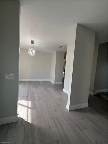 Unfurnished room featuring a chandelier and light wood-type flooring