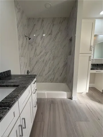 Bathroom featuring vanity, a tile shower, light wood finished floors, and recessed lighting