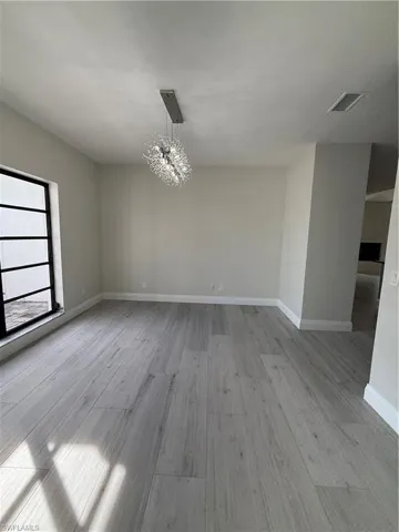 Unfurnished room featuring a chandelier and light wood-style floors