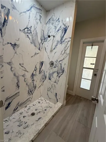 Full bathroom with a marble finish shower and toilet