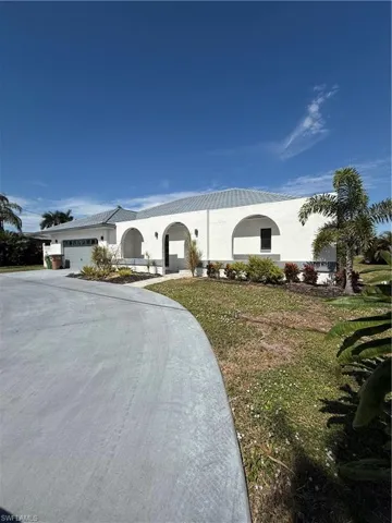View of front of property featuring stucco siding, an attached garage, driveway, and a front yard