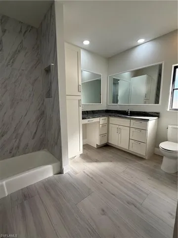 Bathroom featuring vanity, a tile shower, and light wood-type flooring