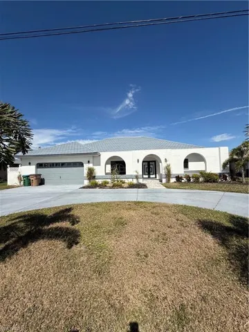 View of front of property with driveway, stucco siding, a front lawn, and an attached garage