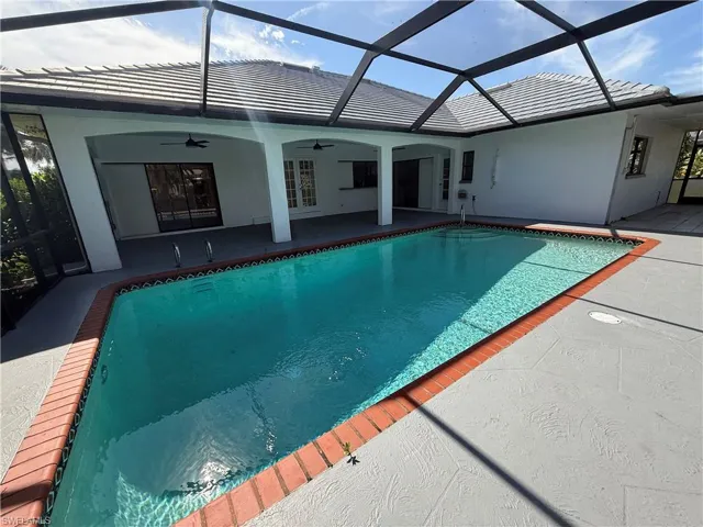 Outdoor pool featuring glass enclosure, a sunroom, and a patio area