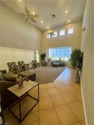 Carpeted living area featuring recessed lighting, a high ceiling, tile patterned floors, visible vents, and a ceiling fan