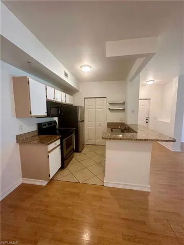 Kitchen featuring visible vents, stainless steel electric range oven, white cabinetry, black microwave, and light wood-type flooring