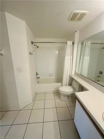 Bathroom featuring a textured ceiling, visible vents, toilet, tile patterned floors, and vanity