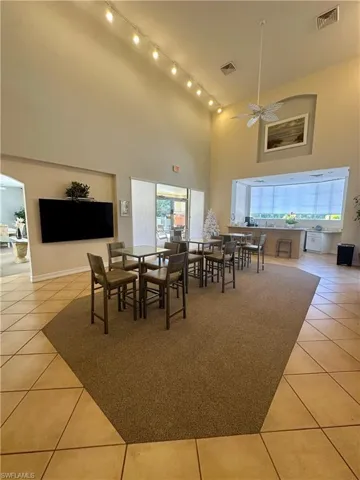Dining room with a high ceiling, light tile patterned floors, and visible vents