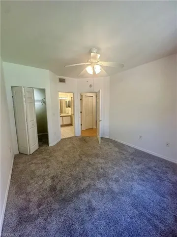 Unfurnished bedroom featuring connected bathroom, baseboards, visible vents, ceiling fan, and carpet