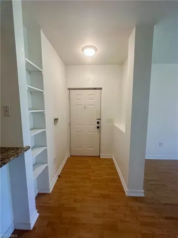Doorway featuring baseboards, light wood-style flooring, and built in features