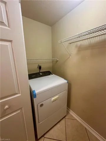 Laundry room with light tile patterned floors, baseboards, laundry area, and washer / dryer