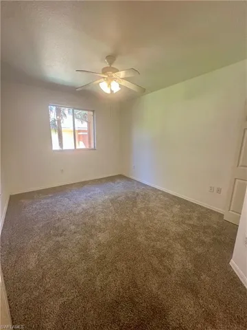 Spare room with baseboards, ceiling fan, carpet floors, and a textured ceiling
