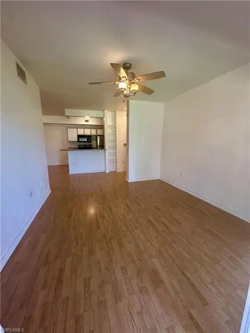 Unfurnished living room with baseboards,  a ceiling fan, and wood finished floors