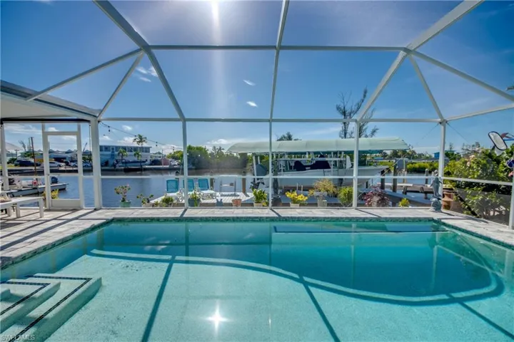 View of swimming pool featuring a lanai, a patio, and a water view