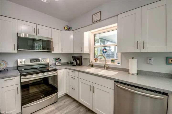 Kitchen featuring light wood-type flooring, white cabinets, appliances with stainless steel finishes, and sink
