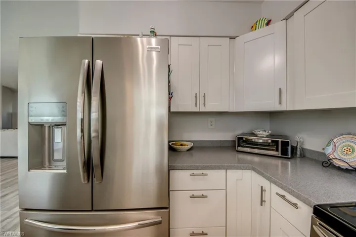 Kitchen with hardwood / wood-style floors, white cabinets, and stainless steel refrigerator with ice dispenser