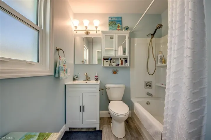 Full bathroom featuring shower / bath combo with shower curtain, toilet, hardwood / wood-style floors, and vanity