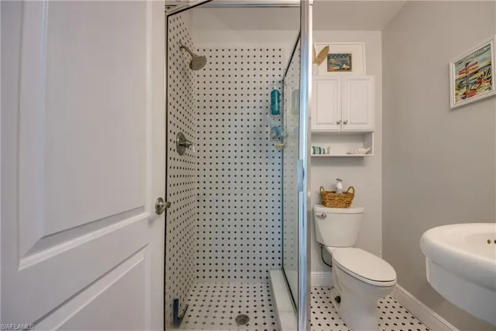 Bathroom featuring walk in shower, toilet, sink, and tile patterned flooring