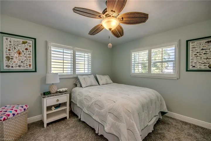 Carpeted bedroom with ceiling fan and multiple windows