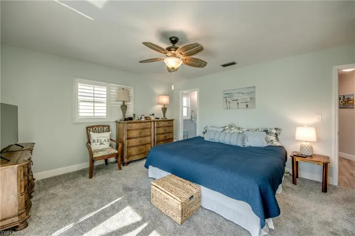 Carpeted bedroom featuring connected bathroom and ceiling fan