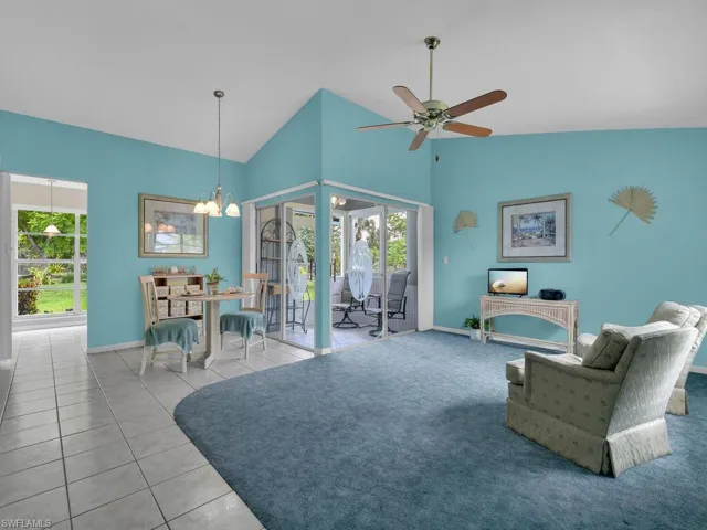 Living room featuring a chandelier, a ceiling fan, tile patterned flooring, and high vaulted ceiling