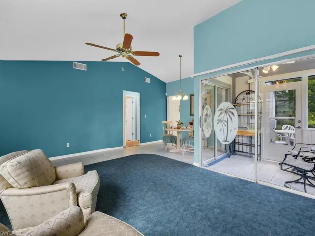 Tiled living room featuring a chandelier, a ceiling fan, and vaulted ceiling
