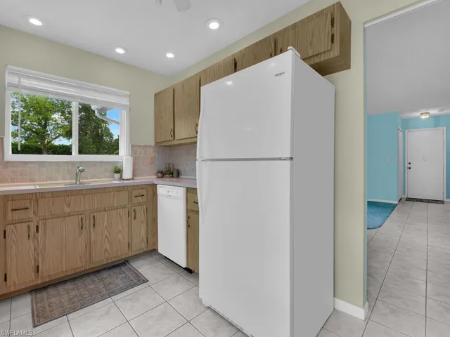 Kitchen featuring white appliances, light countertops, light tile patterned flooring, backsplash, and recessed lighting